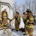 Firefighters outside a training house during the winter.